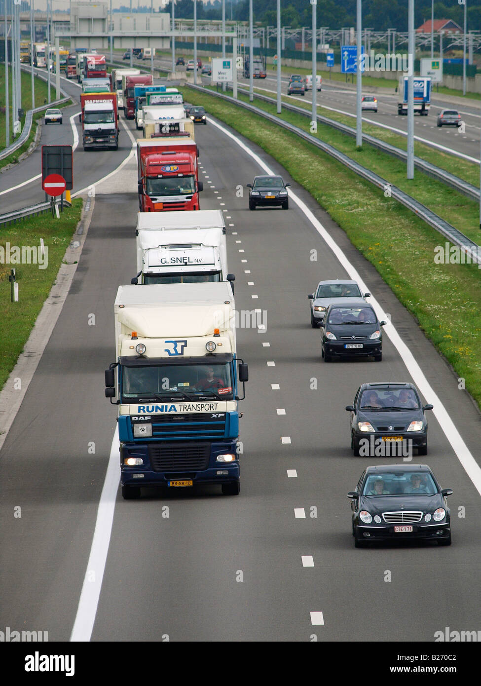 Long line of trucks driving on the A16 E19 road from Antwerp into the Netherlands Hazeldonk Dutch Belgian border Stock Photo