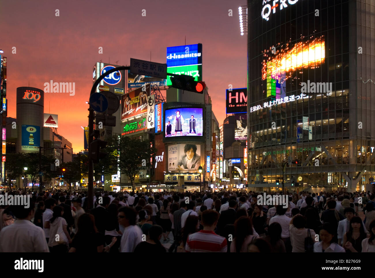 Upscale shopping district Shibuya in Tokyo at the street crossing in front of the main train station at sunset Stock Photo