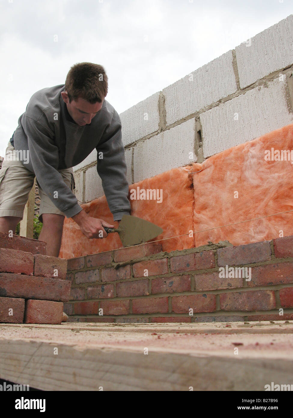 builder / construction worker working on a brick wall cementing bricks