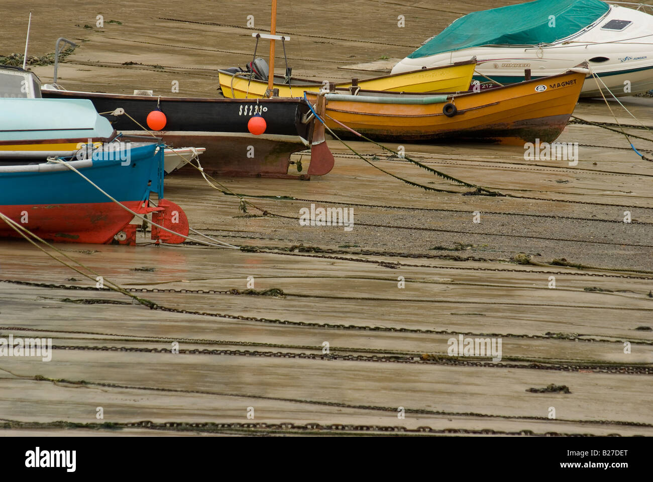Colourful fishing boats moored up in a harbor at low tide in the ...