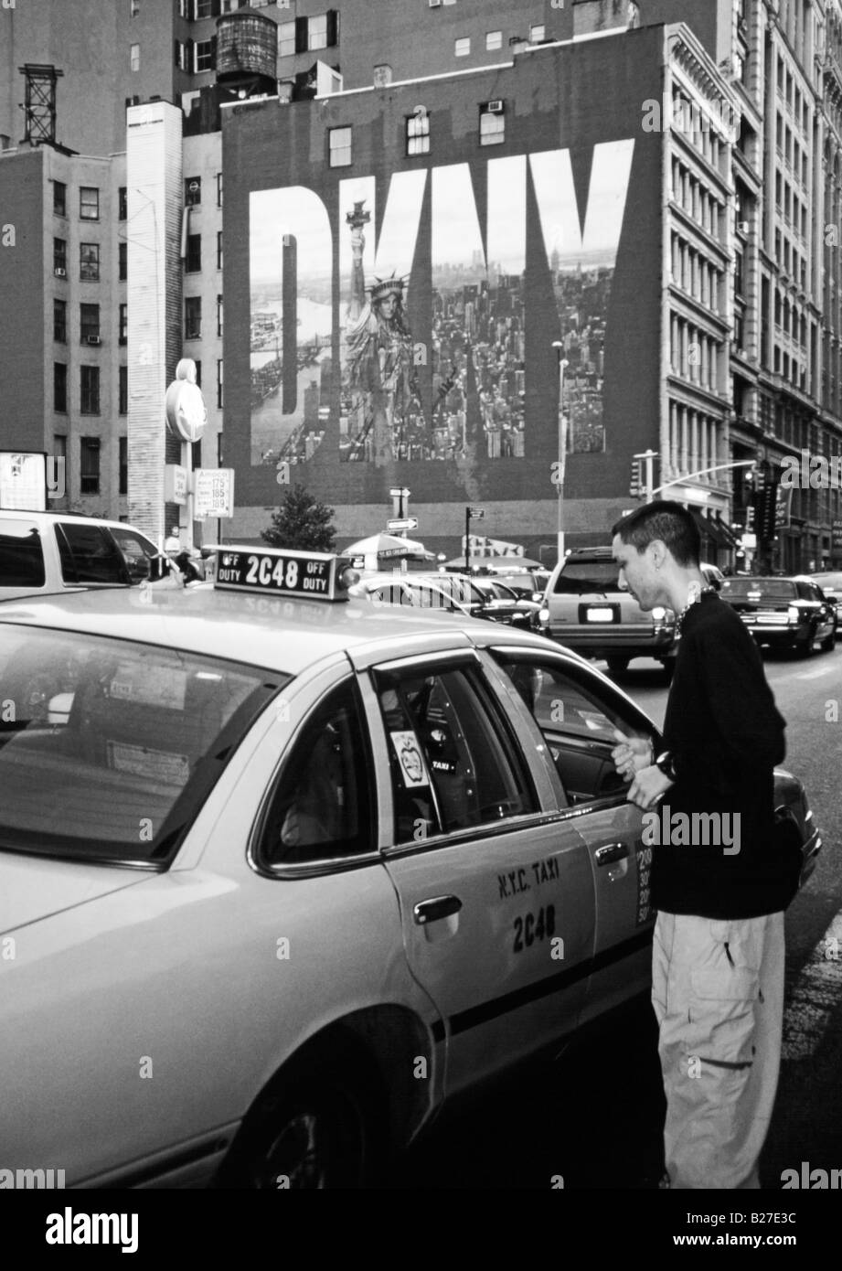Busy street cene, young man paying Manhattan taxi cab fare against New York billboard, New York State, USA Stock Photo