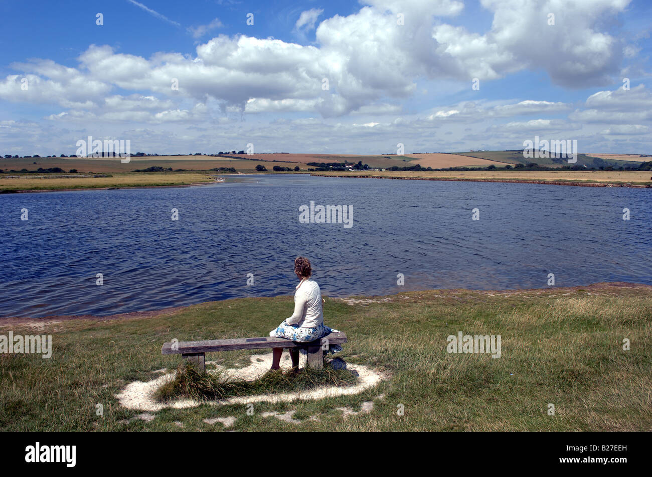 A lady sits watching out over Cuckmere Haven at the Seven Sisters Country Park Stock Photo