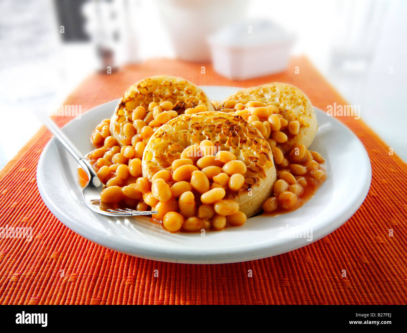 Baked beans on crumpets served as a meal on a white plate in a table setting Stock Photo Alamy