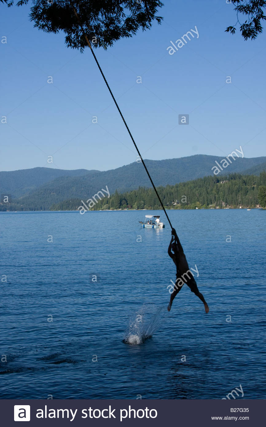 A Silhouette Of A Boy On A Rope Swing Just Before Dropping