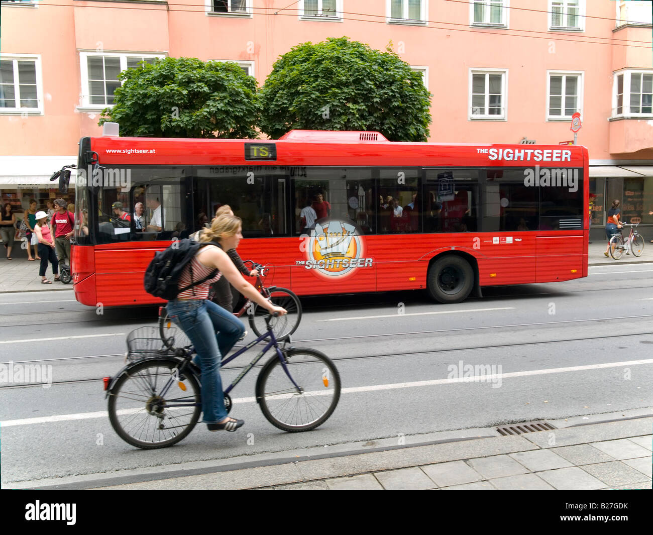 Sightseer bus a special service for tourists in Innsbruck Austria with passing young woman cyclist Stock Photo