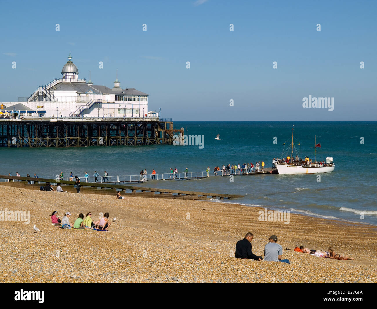 Tourists disembark from a pleasure boat along a floating gangway in summer sunshine by Eastbourne pier East Susssex UK Stock Photo