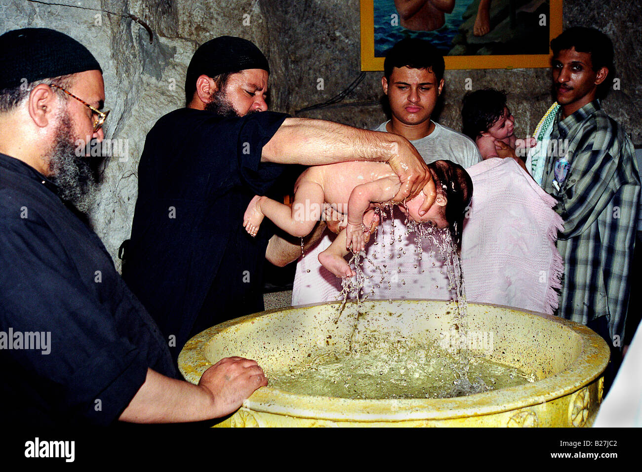 A Coptic priest is baptising a baby boy in the church of a monastery, Deir Al Adra, in Durunka beside Assiut in Upper Egypt Stock Photo