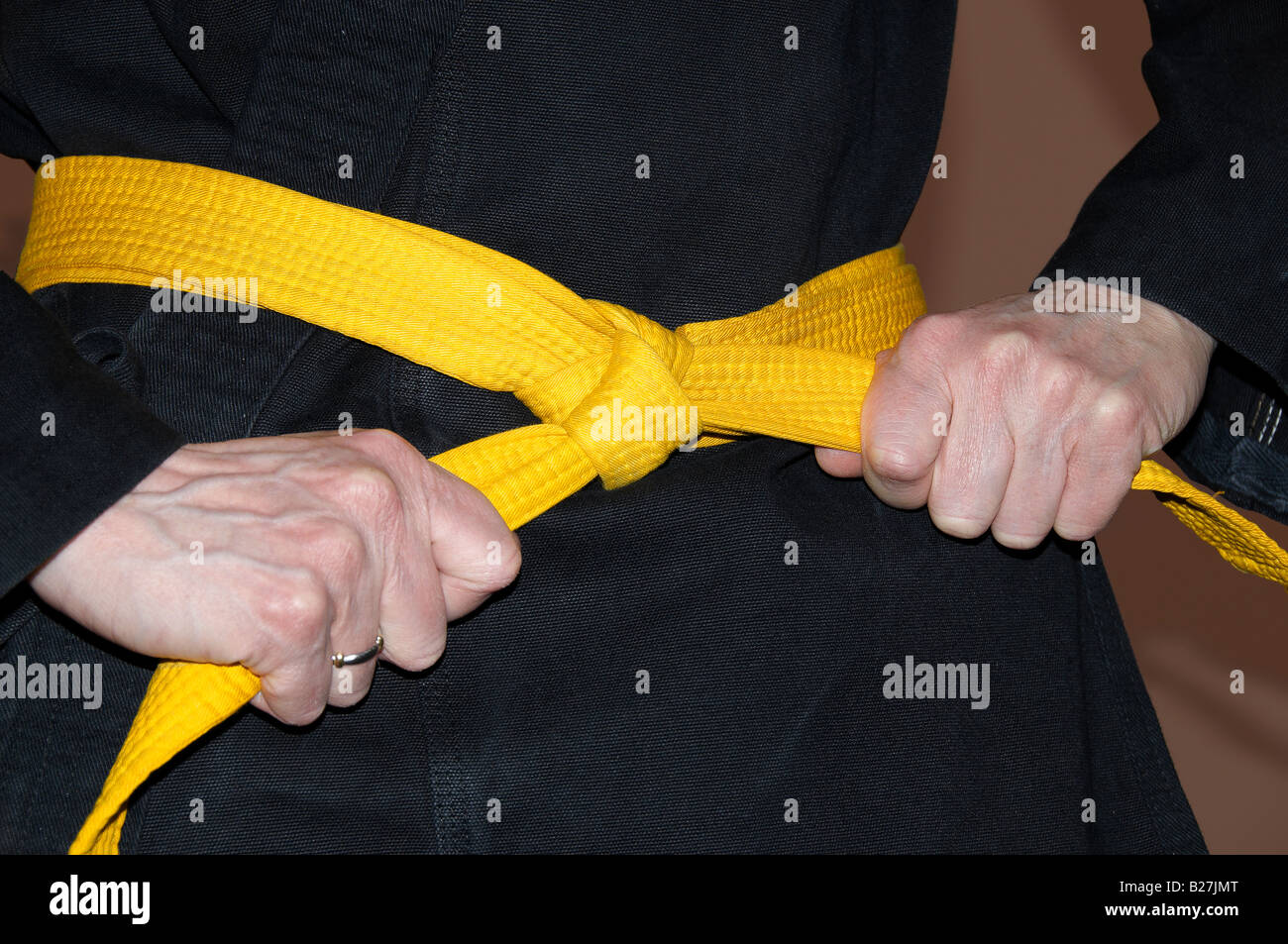 Girl in karate gi tightening yellow belt Clipping path Stock Photo Alamy