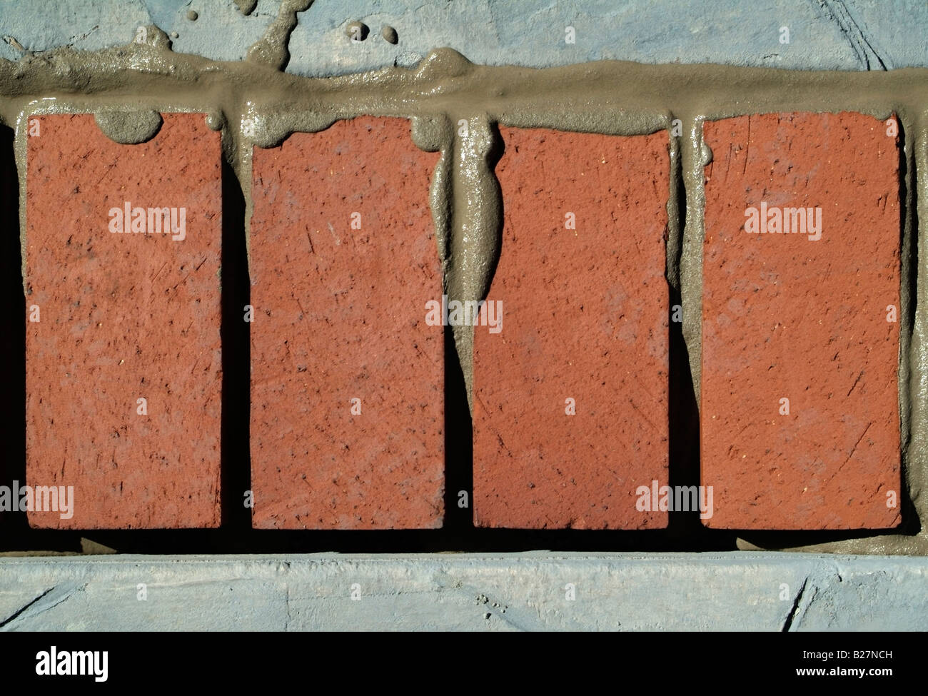 Wet mortar between red clay bricks and stamped concrete slabs making a