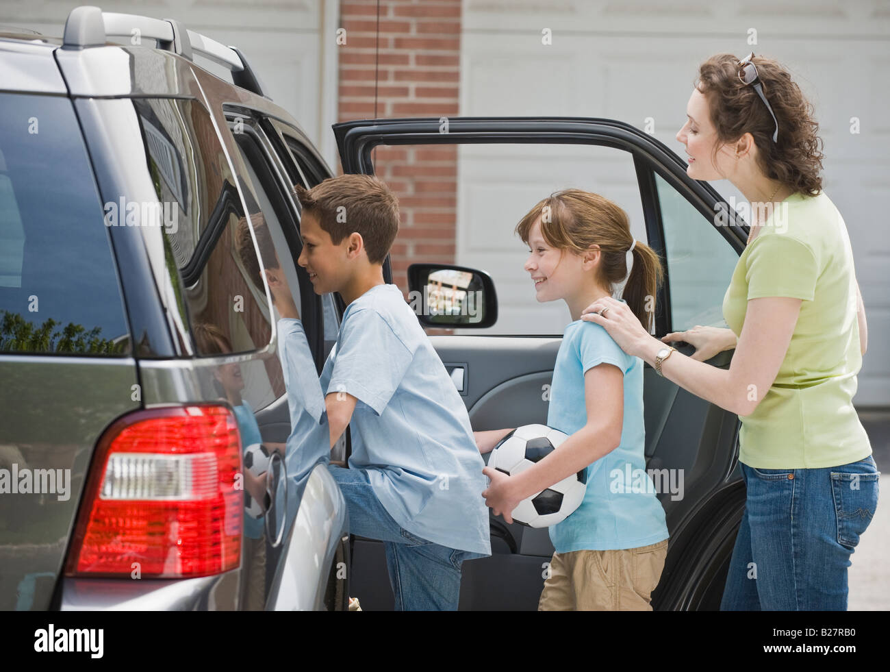 Mother and children getting into car with soccer ball Stock Photo Alamy