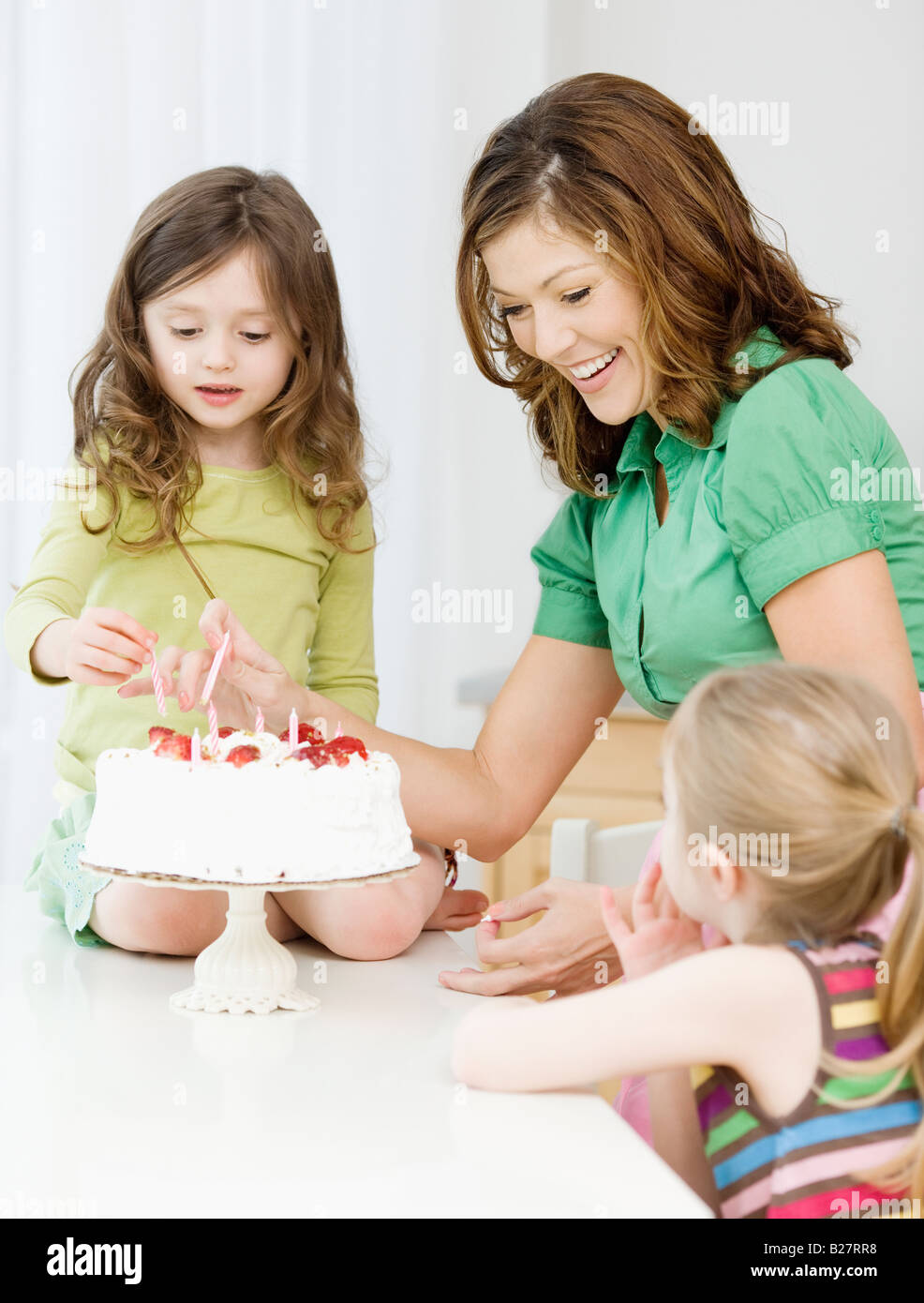 Mother and daughters decorating birthday cake Stock Photo