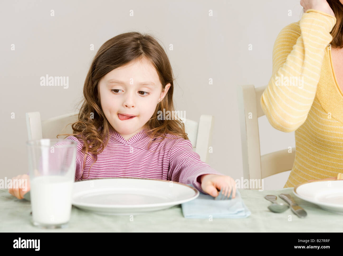 Girl sitting at dinner table Stock Photo