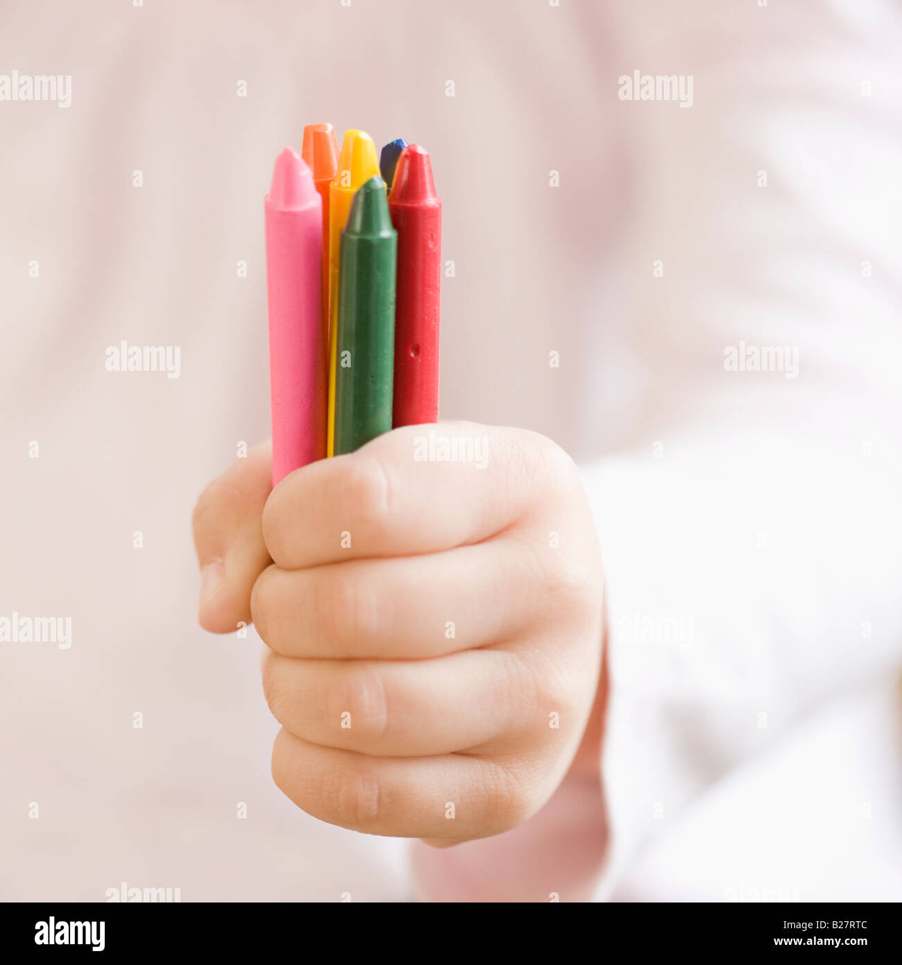 Child holding assorted crayons Stock Photo