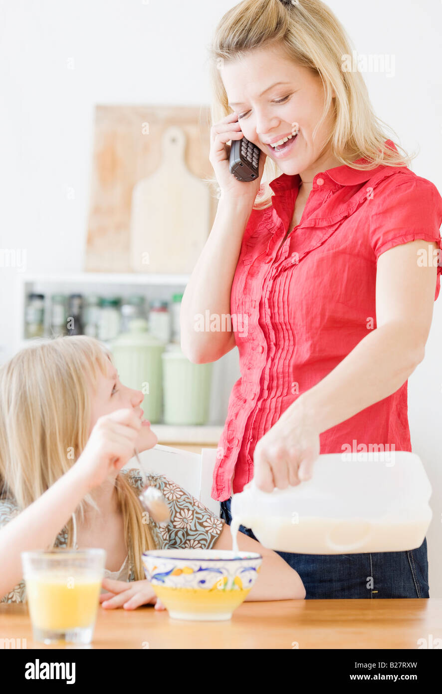 Mother pouring milk into daughter’s cereal Stock Photo