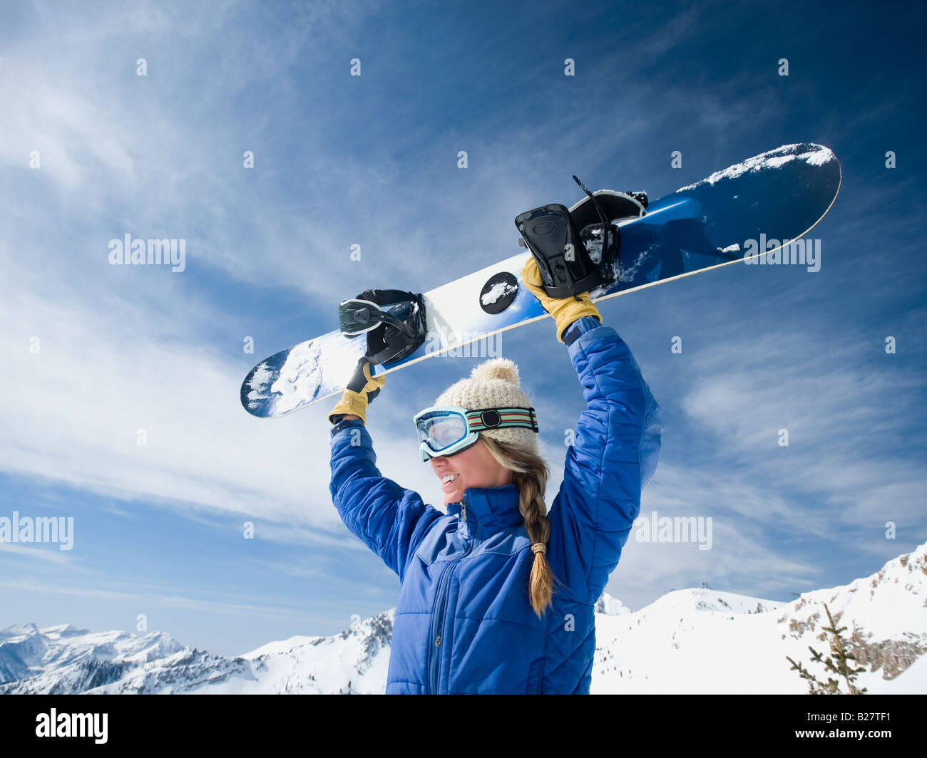 Woman holding snowboard over head Stock Photo Alamy