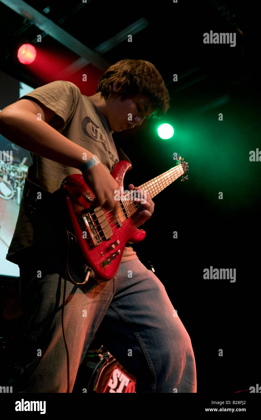 teenage boy playing bass guitar at a gig concert on stage performing live rock music Stock Photo