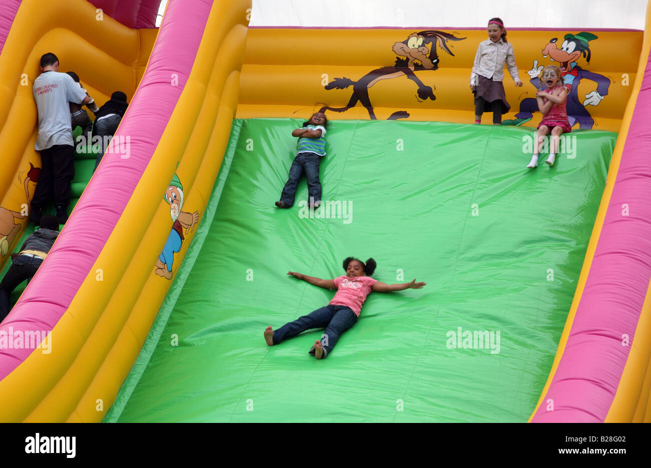 Children enjoying giant inflatable slide at London funfair Stock Photo
