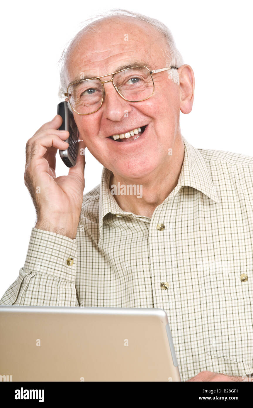 An elderly man at a desk with a lap top computer while talking on a mobile phone against a pure white (255) background. Stock Photo