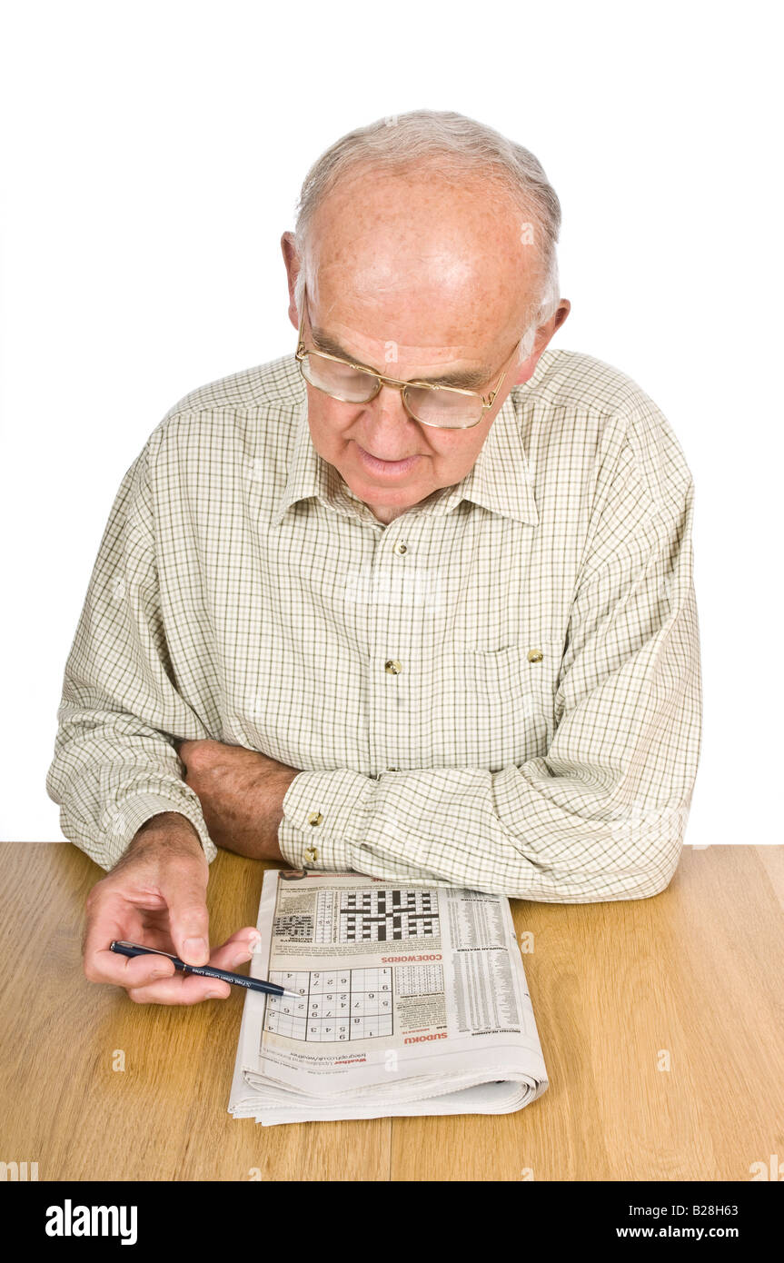An elderly man concentrating on a sudoku puzzle in a newspaper. Stock Photo