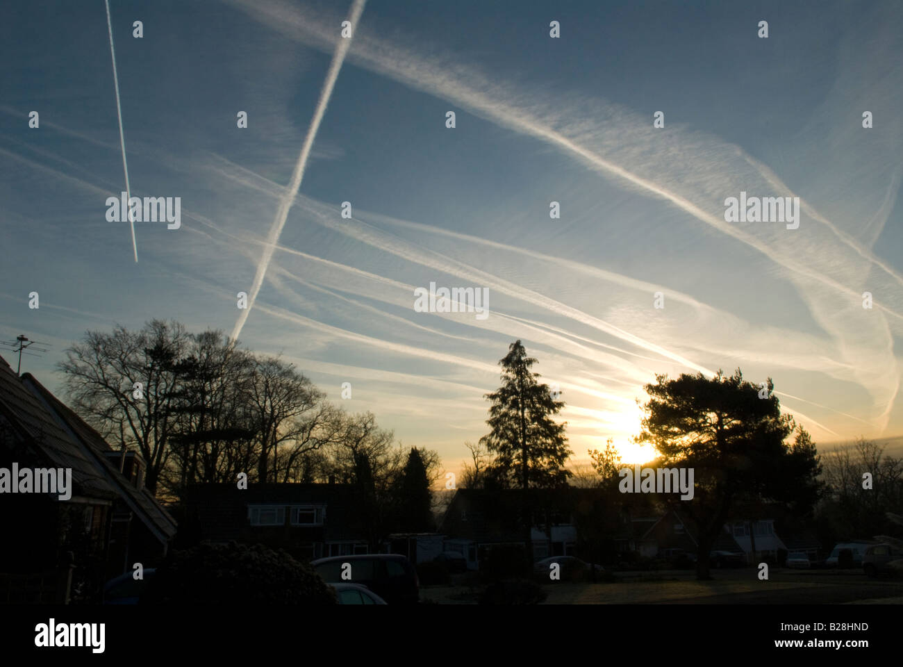 multiple contrails from planes in sky showing flight path over Midhurst, Sussex, UK, Sunrise Stock Photo