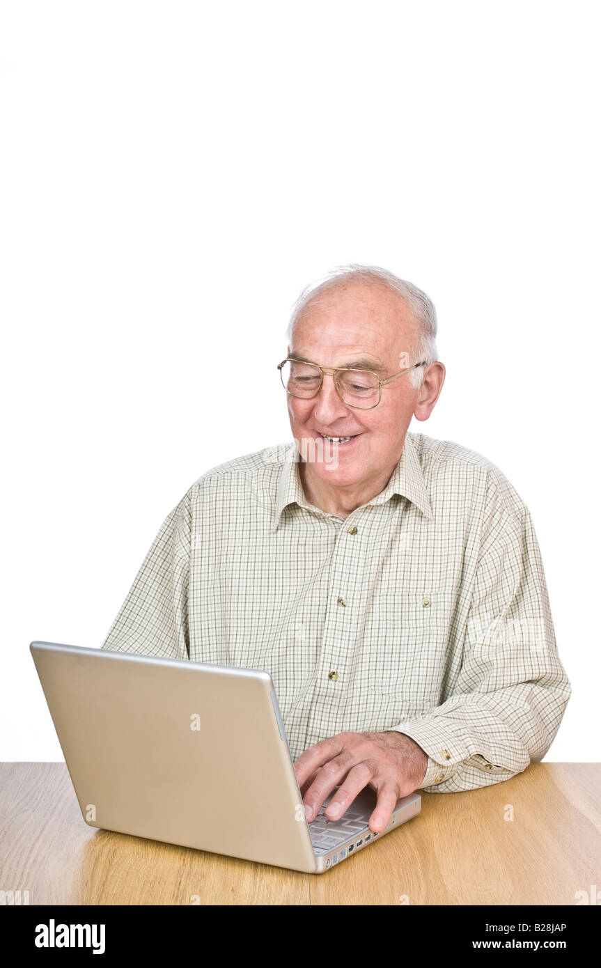 An elderly man at a desk looking at a lap top computer screen and smiling against a pure white (255) background. Stock Photo