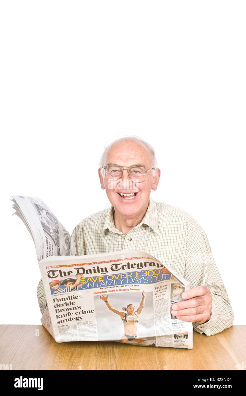 An elderly man smiling while reading a newspaper sat at a desk against a pure white (255) background. Stock Photo