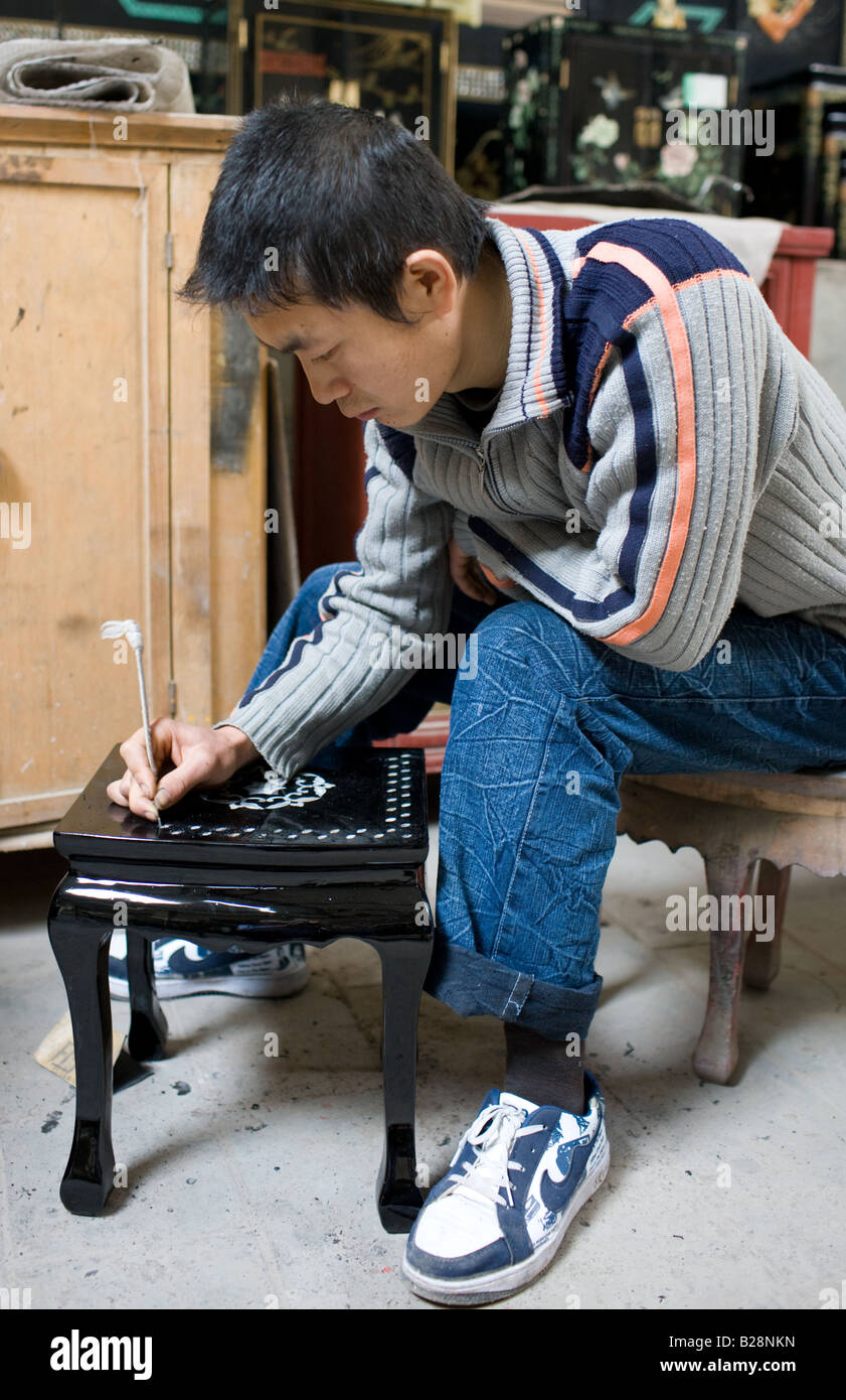 Marquetry craftsman at work on lacquer table at souvenir and furniture