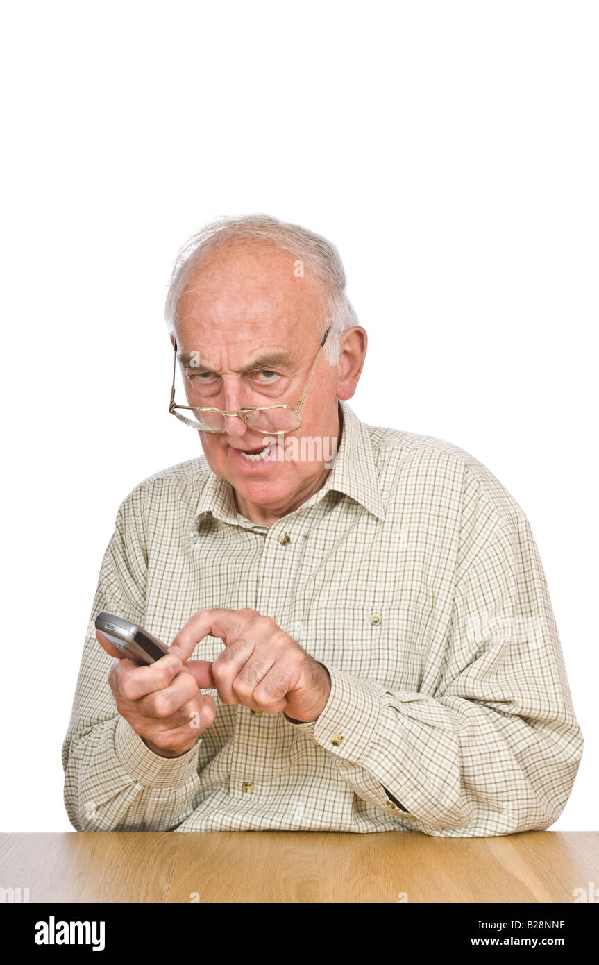 An elderly man getting frustrated trying to text or use the mobile phone with the small buttons and numbers. Stock Photo