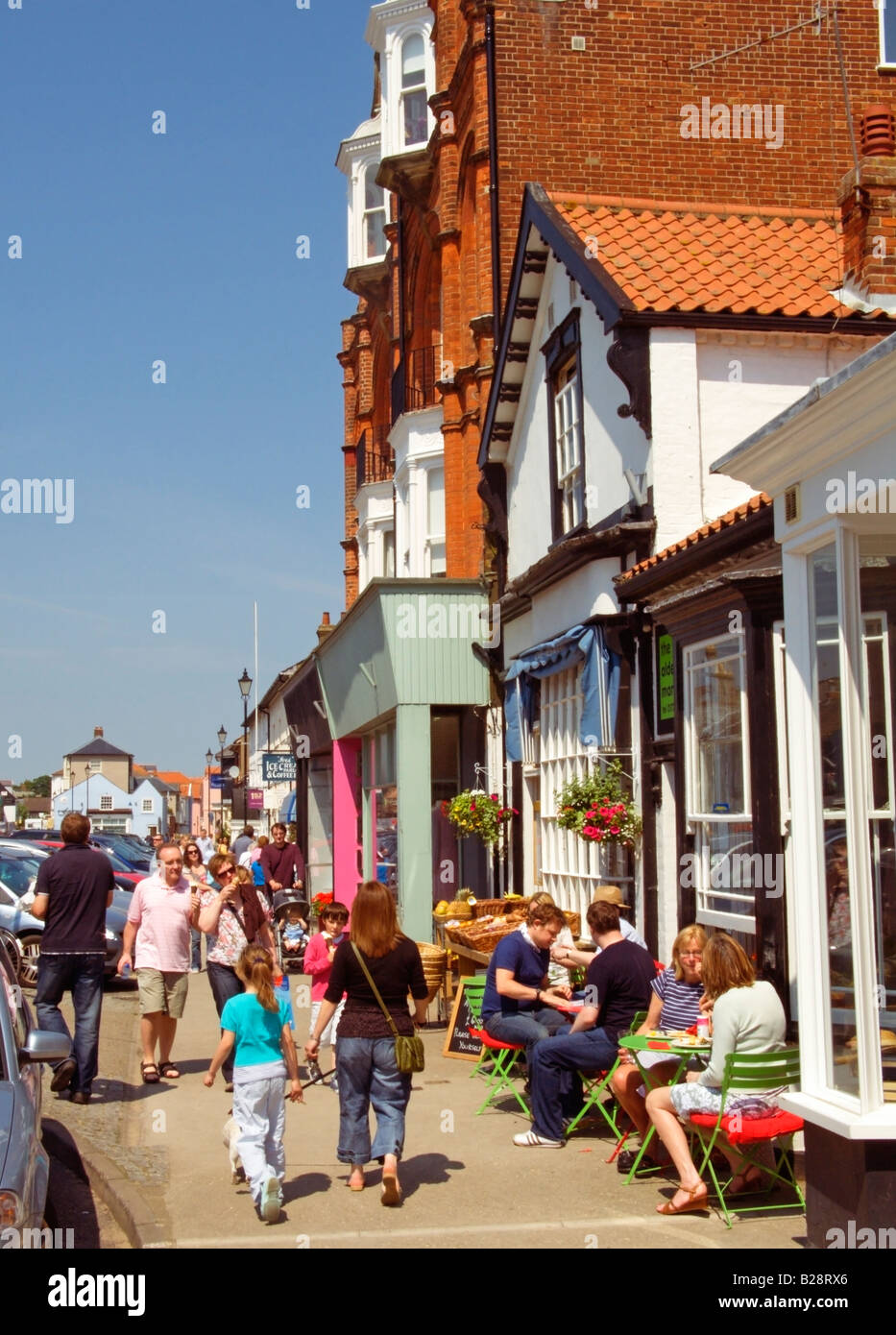 People sitting, drinking and dining in street café and restaurants while busy with tourists along the High Street, Aldeburgh, Suffolk, England, UK Stock Photo