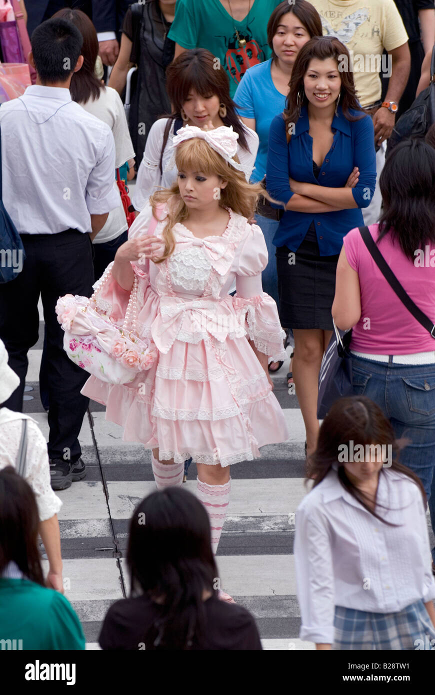 A girl dressed in frilly lolita-style fashion is walking in a crowd crossing a busy Tokyo street Stock Photo