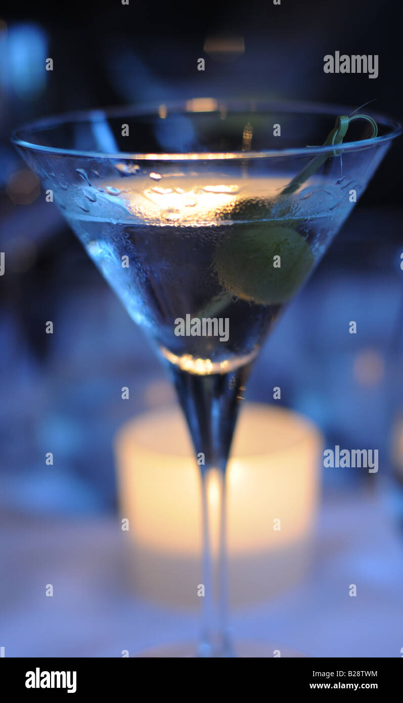 Photograph of a martini with olives, beading with moisture in the summer heat, shimmering in the candle light of a restaurant Stock Photo