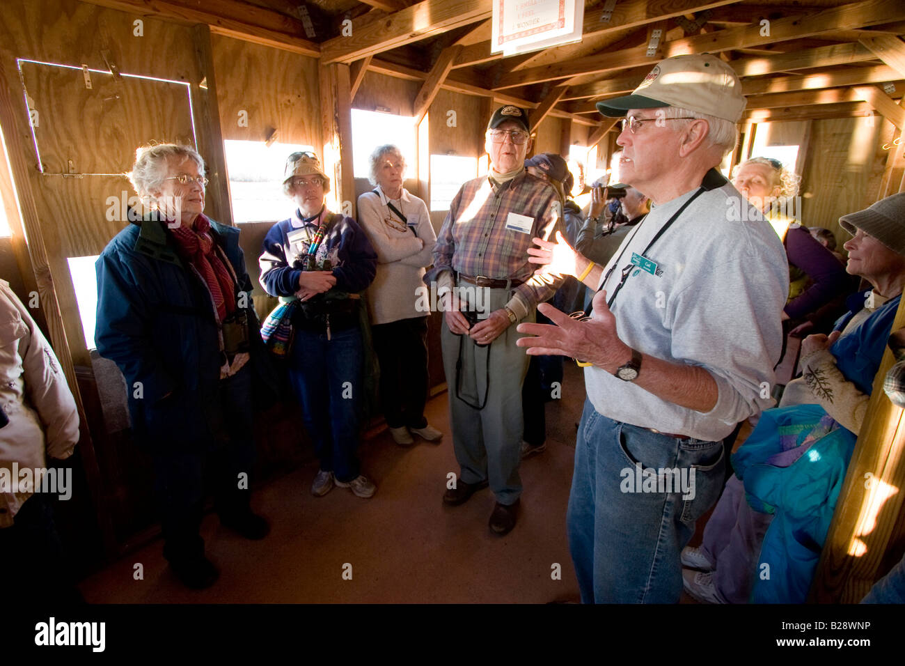 A guide explains the migratory habits of a Sandhill Crane as bird watchers wait for sunset from inside a bird blind Stock Photo