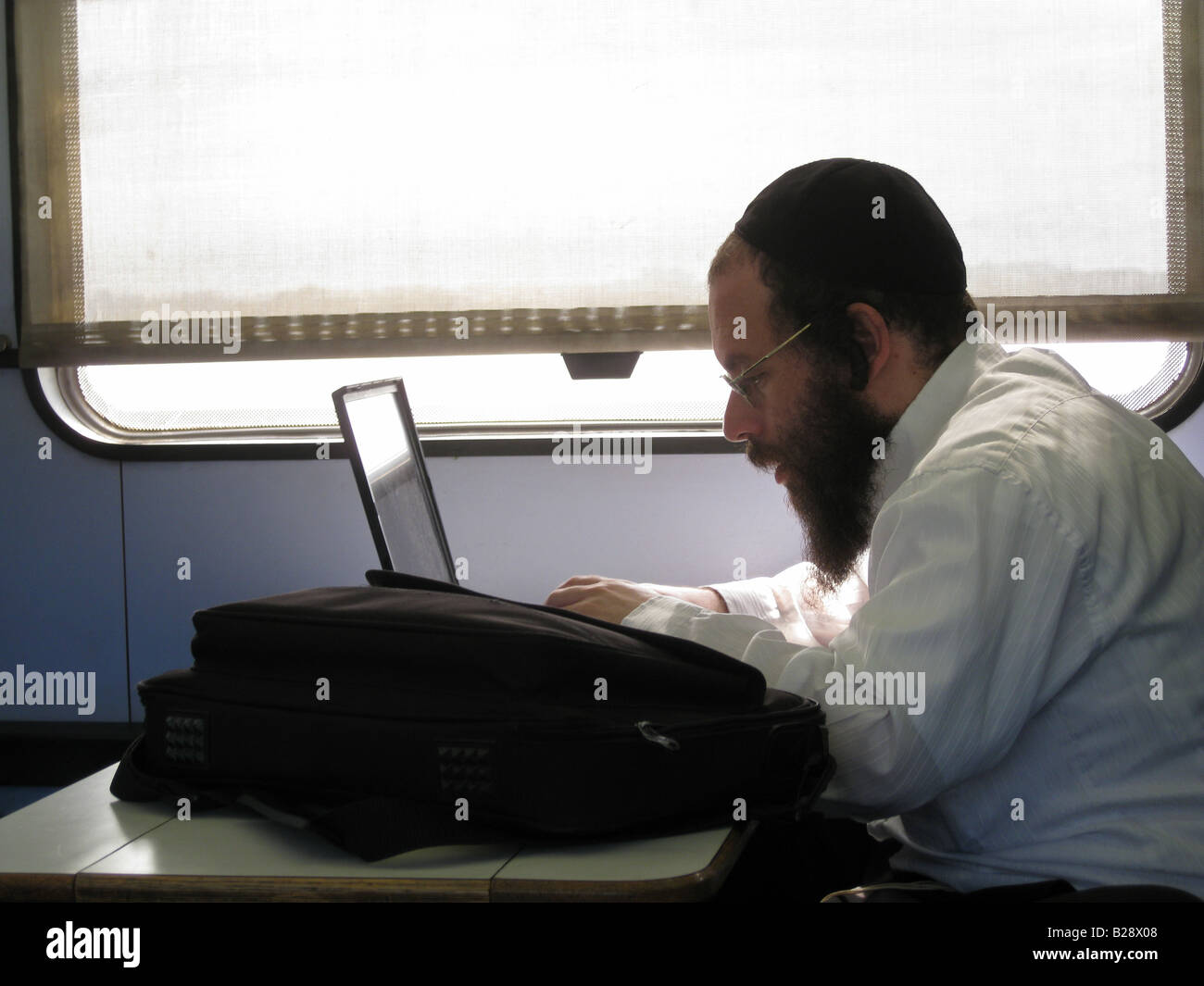 Ultra orthodox Jewish passenger with laptop computer seated in train cabin in Israel Stock Photo