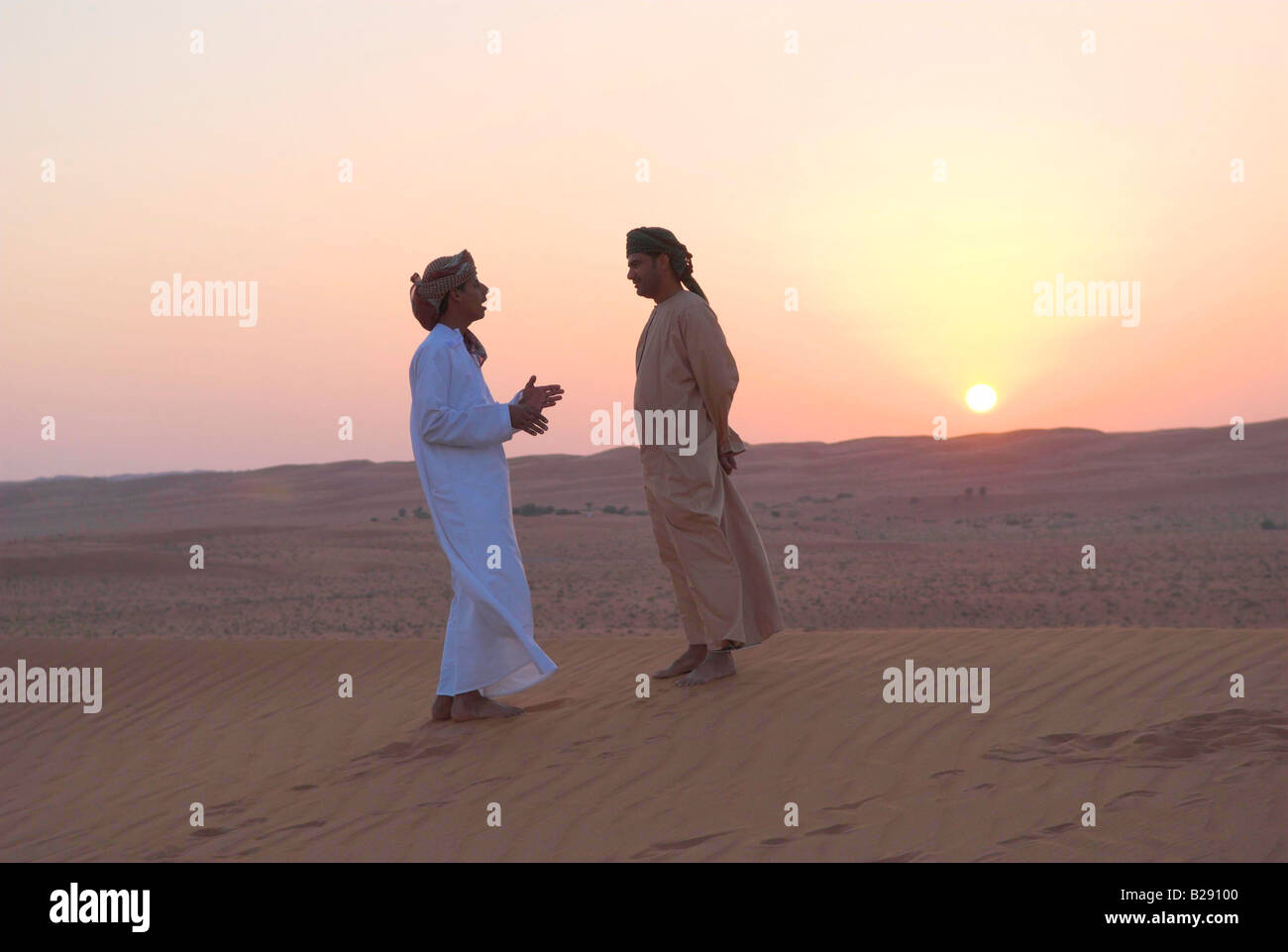Two Omani guides wearing traditional dishdasha Wahiba Sands at sunset Stock Photo