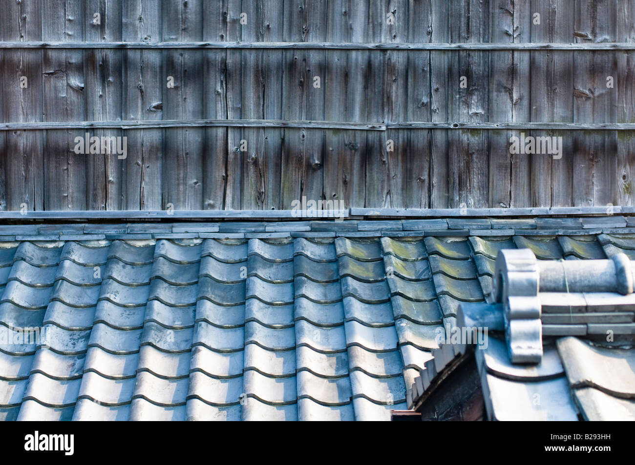 Traditional Japanese ceramic roof tiles with wooden planking and a roof apex in the foreground. Stock Photo