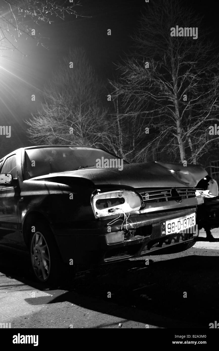 Broken car parked in the street in a dark and cold winter night. Black & White picture. Trees in the Background. Stock Photo