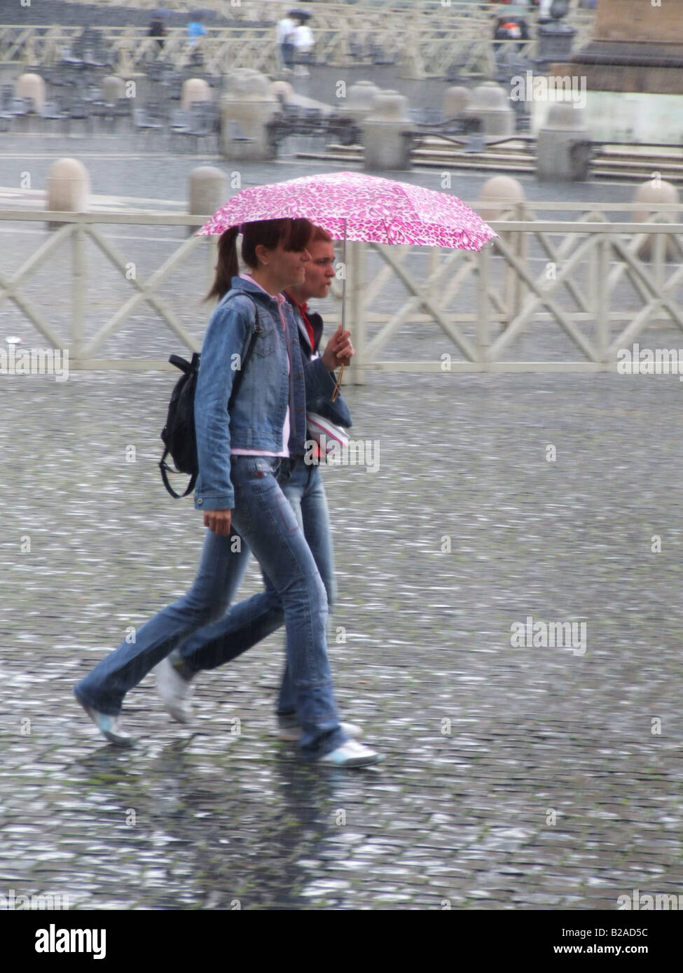two friends sharing umbrella in heavy rain in town Stock Photo Alamy