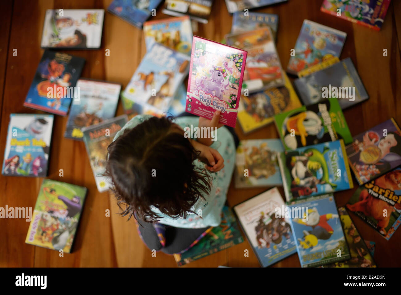 Five year old girl spends time choosing a DVD to watch in the afternoon