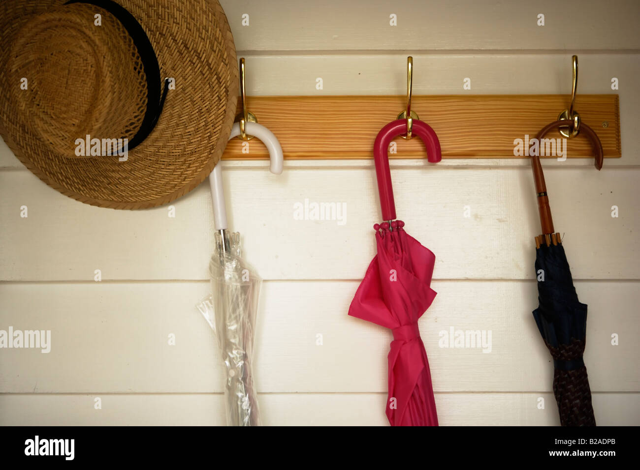 Umbrellas and straw hat hanging from coat rack Stock Photo Alamy