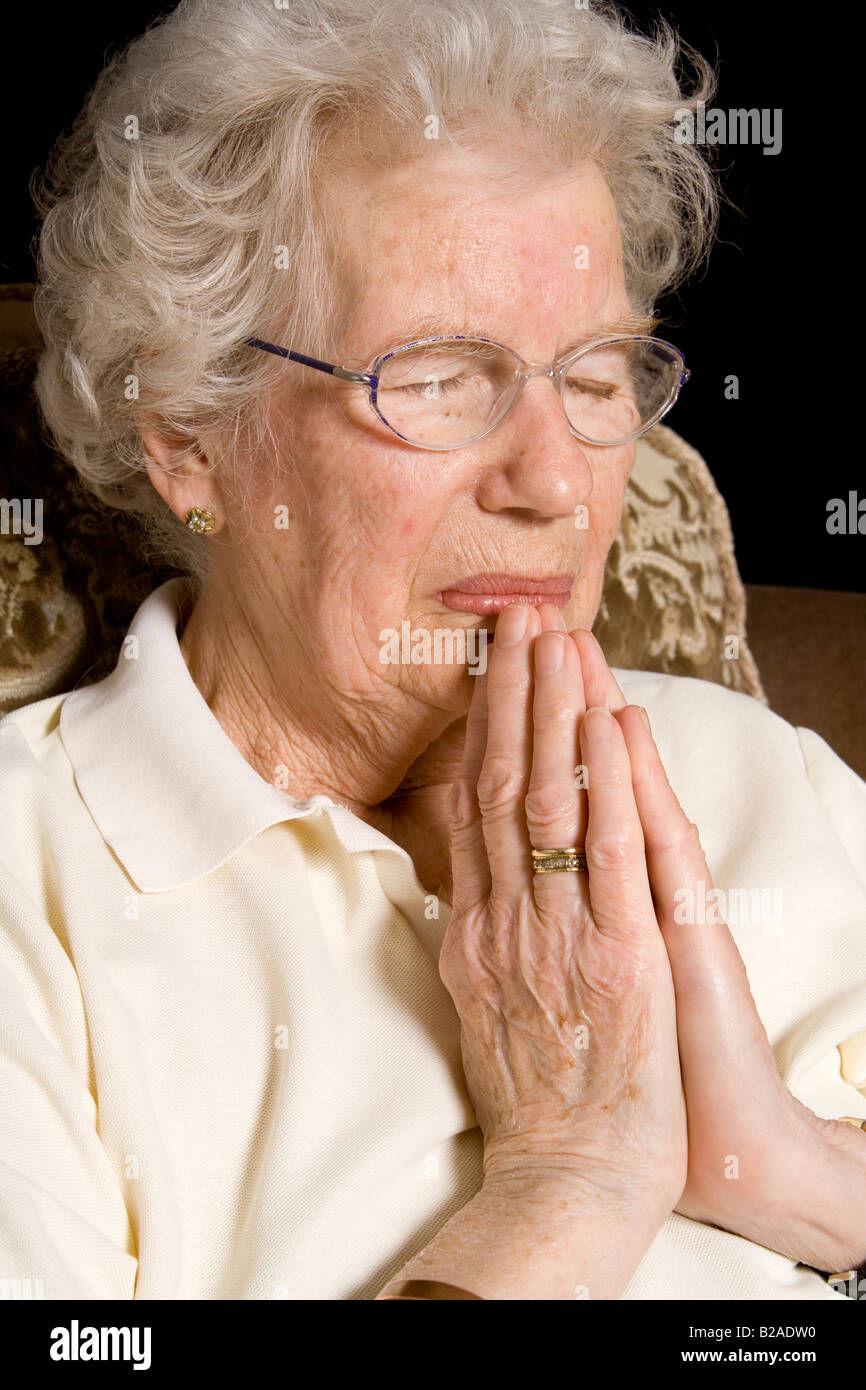 An old woman praying, UK. Stock Photo