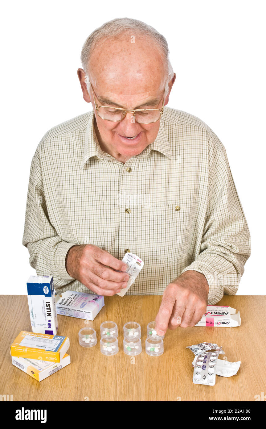 An elderly man sorting his daily dose of pills to take into containers. Stock Photo