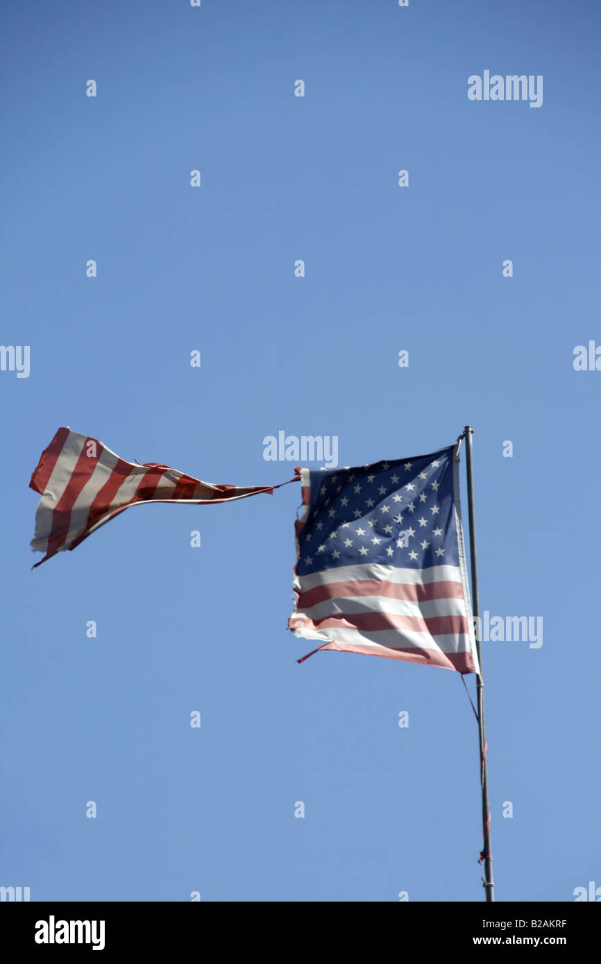 one damaged american flag flying in blue sky Stock Photo - Alamy