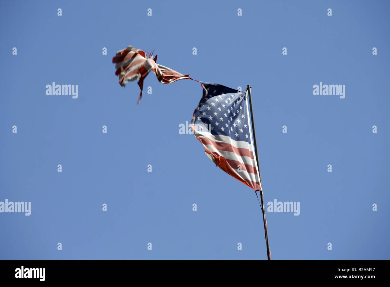 one damaged american flag flying in blue sky Stock Photo - Alamy