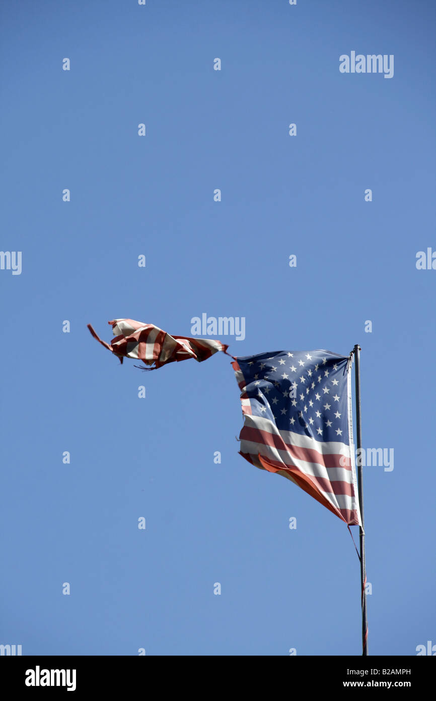 one damaged american flag flying in blue sky Stock Photo - Alamy