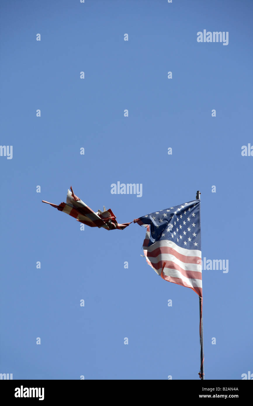 one damaged american flag flying in blue sky Stock Photo - Alamy