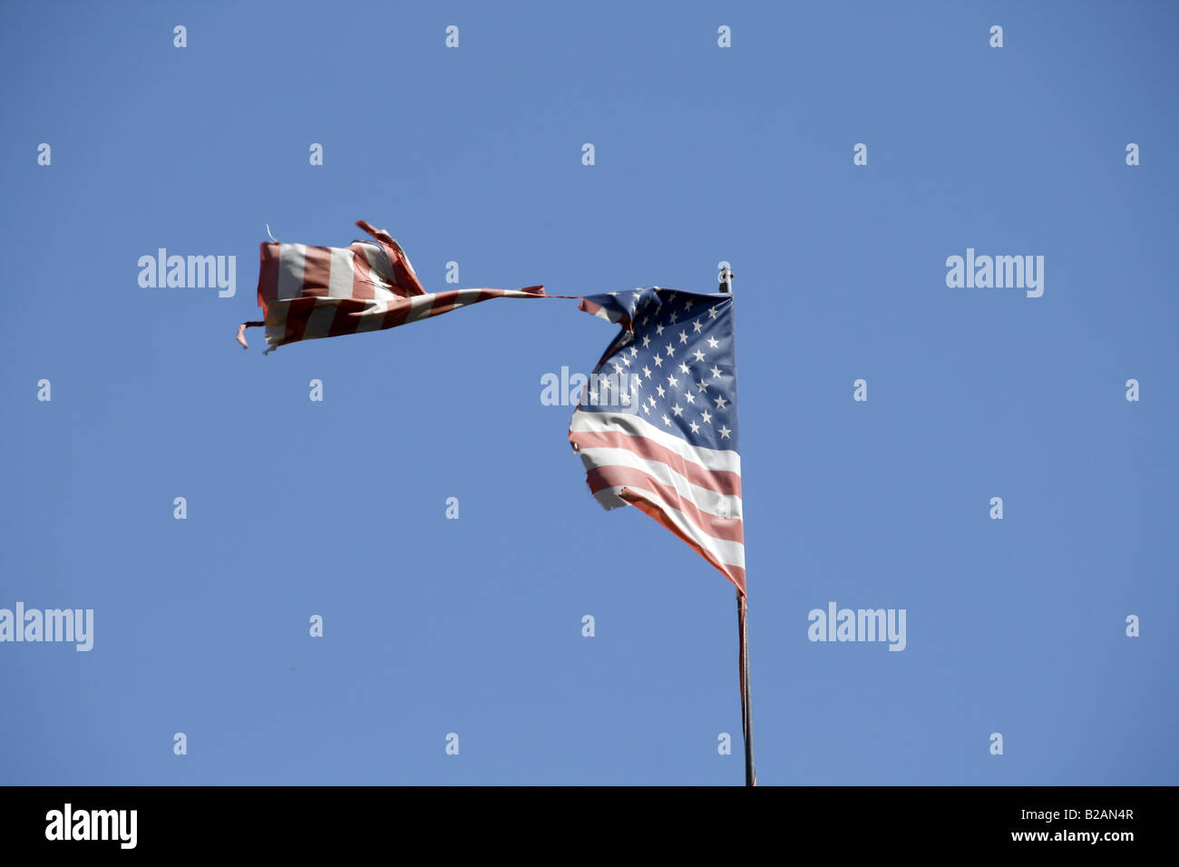 one damaged american flag flying in blue sky Stock Photo - Alamy