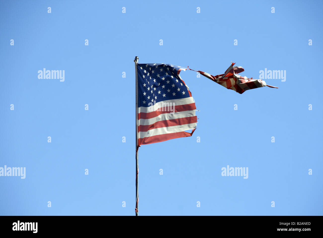 one damaged american flag flying in blue sky Stock Photo - Alamy