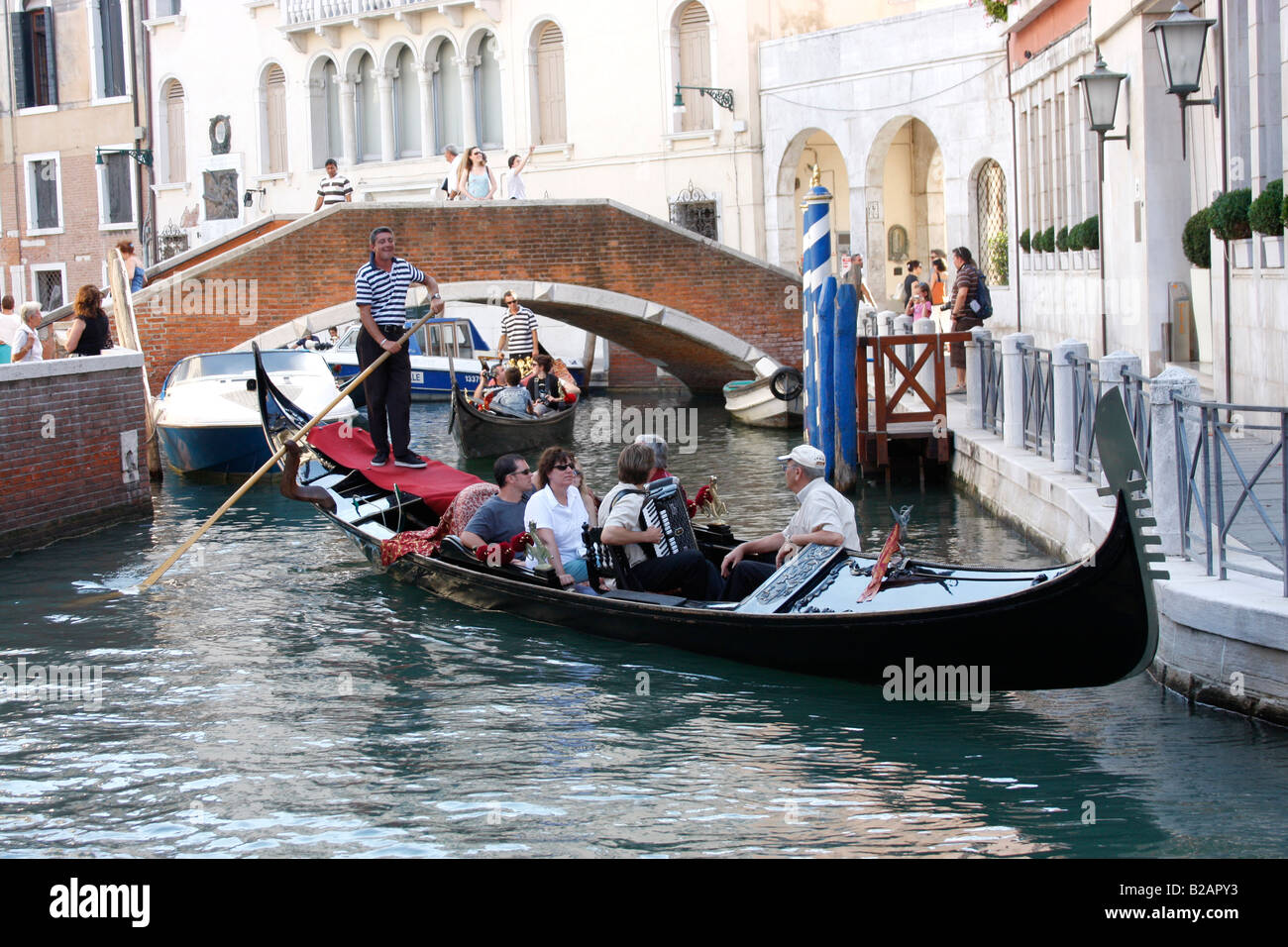 Tourists enjoying an evening Gondola ride along the Venice canals listening to music from an accordion. Stock Photo