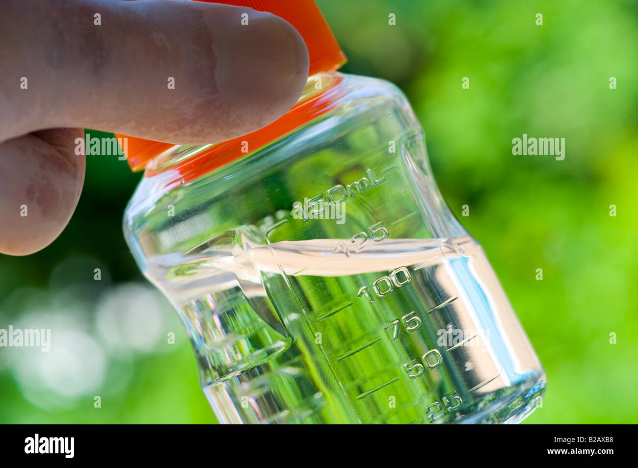 hand holding  small vial of clear fluid outdoors Stock Photo