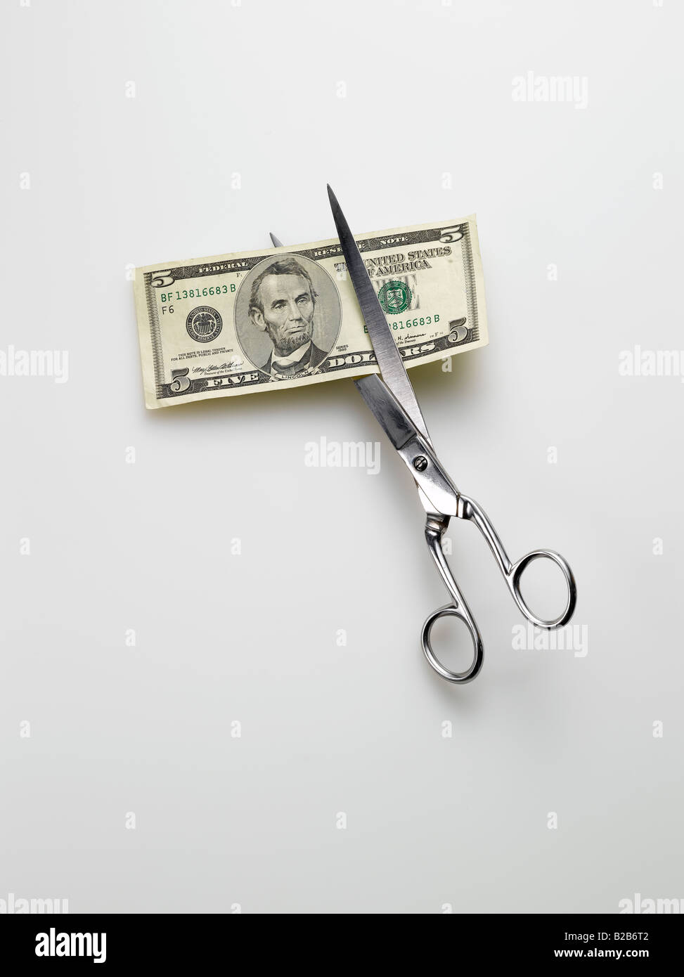 scissors cutting American 5 five dollar bill money on white background Stock Photo